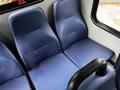 Seating area of a 2019 Chevrolet Express featuring two blue vinyl seats with a textured pattern and a black armrest between them