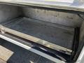 An empty metal storage compartment with a sliding tray inside a 2004 Freightliner M2