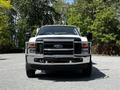 A 2009 Ford F-550 truck with a shiny chrome front grill and visible headlights parked in a green setting