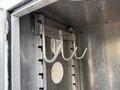 Three metal hooks mounted on a vertical metal frame inside a vehicle compartment