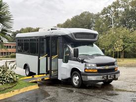A 2020 Chevrolet Express bus with a low entrance ramp extended is parked with its doors open