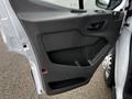 A close-up of the driver's side door panel of a 2021 Ford Transit featuring a textured design and controls for windows and locks