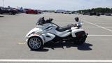 A 2013 Can-Am Spyder with a sleek white and black design featuring two front wheels and a single rear wheel parked in a lot