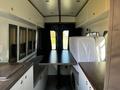 Interior of a 2017 Ford Transit featuring a table with benches along the sides and storage cabinets above the seating area