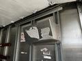 A metal storage box mounted on the interior wall of a delivery truck with visible wear and tear on its surface