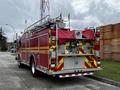 A red 2009 Spartan Gladiator fire truck with yellow and white reflective stripes a ladder on top and various emergency lights and equipment visible at the back