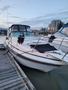 A 1991 Larson Mirado boat is docked with a black cover on the front and lights along the sides on a wooden pier