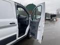 A 2018 Ford Transit van with the driver's side door open showcasing the interior seating and dashboard area