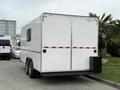 A white 2025 Shuttle Office trailer with dual axles featuring a rear entry door and horizontal red stripes across the body