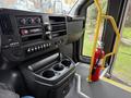 Interior view of a 2013 Chevrolet Express showing the dashboard with controls a cup holder and a fire extinguisher mounted on the side