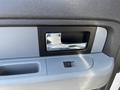 Close-up of the door handle and window controls of a 2014 Ford F-150 interior featuring silver and gray accents