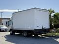 A white 2013 Isuzu NPR box truck parked with a large rectangular cargo area and a flatbed design