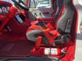 Interior of a 1962 Ford F-100 featuring red and black leather seats a steering wheel with a polished metal column and a fire extinguisher on the floor