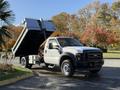 A 2008 Ford F-550 dump truck with a raised bed revealing its cargo area and side mirrors extended