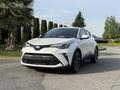 A white 2021 Toyota C-HR parked with a sleek design featuring distinctive headlights and a sporty front grille