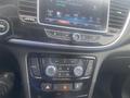 Dashboard of a 2018 Buick Encore featuring climate control buttons and a touchscreen display with music playback information