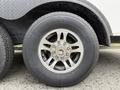 Close-up of a silver alloy wheel with a multi-spoke design mounted on a black tire featuring visible tread patterns