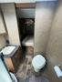 Interior view of a 2014 Launch 24RLS camper showing a bathroom area with a toilet and sink along with a small bed visible in a side compartment