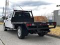 A white 2020 Ford F-350 with a flatbed and dual rear wheels parked on a street showcasing its rear view and extensive storage capabilities