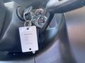 A 2012 GMC Savana key attached to a keyring next to the ignition with a white tag displaying information about the vehicle
