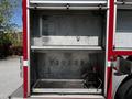 A 2006 Emergency One Fire Truck with an open storage compartment showcasing metallic shelves and a black equipment box on the floor