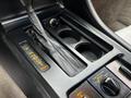 Center console of a 1992 Chevrolet Corvette featuring a leather-wrapped gear shifter two cup holders and various control buttons