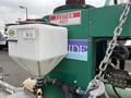 A green machine with a warning label cautions hot water usage and features a white tank attached to a dual flat deck trailer designed for weed control