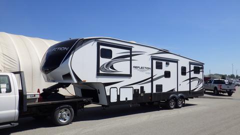 A 2021 Grand Design Reflection 311BHS recreational vehicle with a white exterior and black accents, featuring multiple slide-outs and a modern design