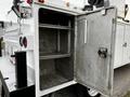 A 2016 Ford F-550 with an open, empty metal storage compartment featuring shelves and a sturdy latch on the door