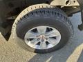 Close-up of a silver alloy wheel on a 2018 GMC Sierra 1500 featuring a large all-terrain tire with a prominent tread pattern and the GMC logo in the center