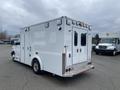 A white 2014 Chevrolet Express with a boxy design featuring rear doors and multiple lights on the top and sides