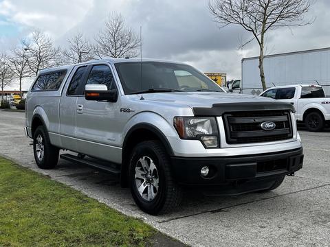 A silver 2014 Ford F-150 with a black grille and chrome accents parked on a paved surface