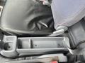 Interior view of a 2008 Mitsubishi Fuso FE180 showing the driver's seat with a grey fabric surface and a storage compartment between the seat and center console
