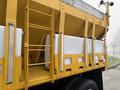 A 2016 International 7400 dump truck with a yellow body and white side compartments designed for hauling materials