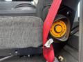 A close-up of a seat belt release button on a 2006 E-One Typhoon showing orange button with FWD and BACK arrows above a gray seat fabric