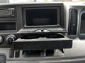 A close-up of the dashboard of a 2015 Mitsubishi Fuso FE showing an open storage compartment and a cup holder beneath it