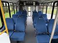 Interior of a 2013 Chevrolet Express bus featuring rows of blue fabric seats with safety belts and a clean aisle running down the middle