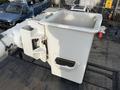 A white bucket attached to a utility vehicle with a rectangular opening on the side and a small door for access