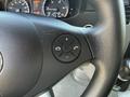 Close-up of a black steering wheel with a control panel featuring buttons for phone functions and volume adjustment in a 2016 Mercedes-Benz Sprinter