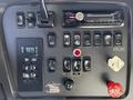 Control panel of a 2012 Freightliner M2 112 featuring various switches knobs and a car stereo system