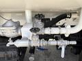 A silver valve assembly with multiple knobs and levers attached to pipes and fittings on a truck's body