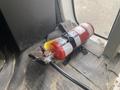 A fire extinguisher is secured to the floor of a vehicle with a strap and has a gauge and nozzle attached