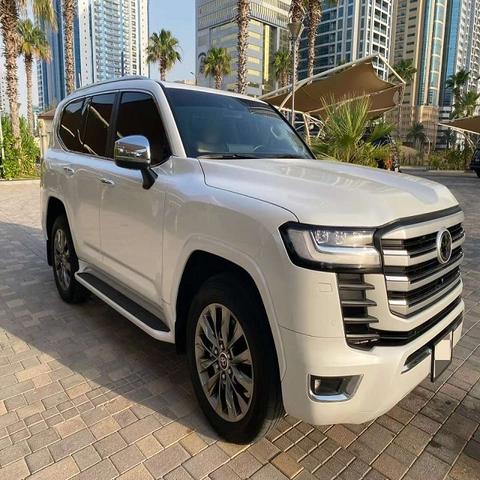 A white 2022 Toyota Land Cruiser GXR parked with its distinctive front grille and large alloy wheels visible