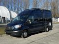 A black 2017 Ford Transit van featuring a roof rack and large windows with a sleek exterior design