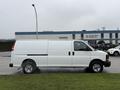 A white 2014 GMC Savana van is parked with a side view showcasing its sliding door and large cargo space