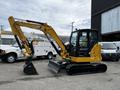 A yellow 2024 Caterpillar 306 excavator with a cab and a prominent bucket attached to the arm positioned on a concrete surface