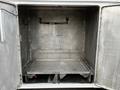 A spacious metallic cargo area with a flat platform and hooks on the wall designed for storage in a 2016 Ford F-550