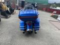 A blue 2017 Harley-Davidson FLHTKL motorcycle featuring a large rear trunk and dual exhaust pipes