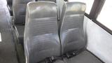 Two gray fabric seats designed for a bus interior with a textured surface and seatbelts attached