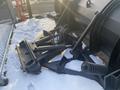 A black 2000 plow with a 12-foot attachment featuring hydraulic arms springs and cables positioned on snow-covered ground